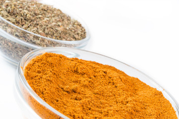 Curry Powder in glass bowls with blurry italian herbs. Culinary concept with curry, italina herb mix