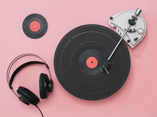 Black headphones with wire and a vintage player on a pink background.