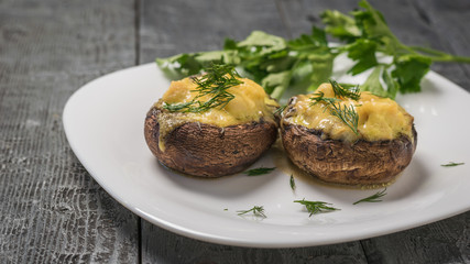 Mushrooms baked with cheese and herbs on a wooden table.