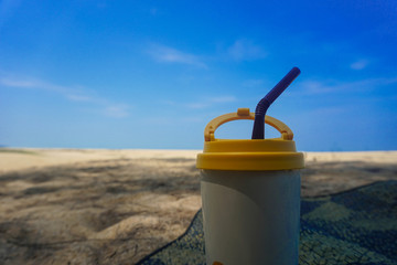 Stainless steel coffee mug on the sand behind the sea