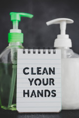 keep clean to fight bacteria and viruses, hand sanitizer and liquid soap next to memo with Clean your Hands text