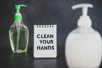 keep clean to fight bacteria and viruses, hand sanitizer and liquid soap next to memo with Clean your Hands text