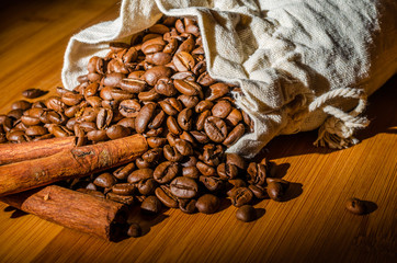 Coffee beans with cinnamon sticks in a cloth bag