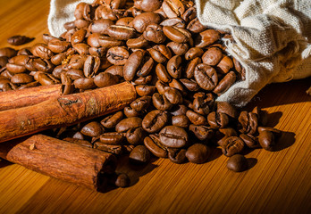 Coffee beans with cinnamon sticks in a cloth bag