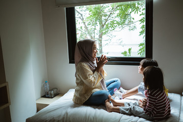 mother storytelling to her daughter on the bed play together