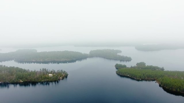 Aerial shot of small islands with dense forest, a calm lake and a small settlement (Willard Lake, Ontario, Canada)