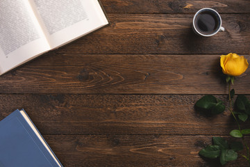 Morning cozy concept. Open books, cup of coffee, rose, on wooden background. Flat lay, top view, copy space.