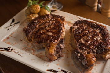 grilled beef chop with small roasted potatoes on a rectangular white plate