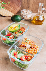 Healthy meal prep containers with chickpeas, chicken, tomatoes, cucumbers and avocados. Healthy lunch in glass containers on beige rustic background. Zero waste concept. Selective focus.
