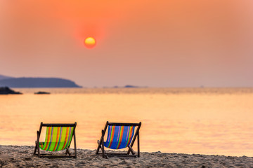Beautiful early sunset over two deck chairs on the sandy tropical beach and Wave of the sea on the sand beach the horizon Summer time at hat sai kaew beach in Chanthaburi Thailand.