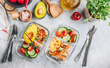 Healthy meal prep containers with chickpeas, chicken, tomatoes, cucumbers and avocados. Healthy lunch in glass containers on light gray background. Zero waste concept. Top view. Flat lay