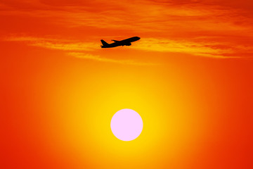 Naklejka na ściany i meble A beautiful silhouette of a plane taking off from the Don Mueang International Airport in the morning or near dusk, with the backdrop of a big sun and a thin cloud in the travel and tourism concept.