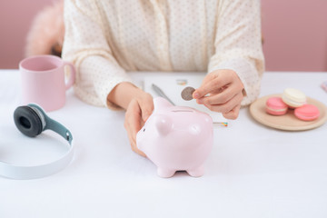 Woman hand Putting Coin In Piggy Bank, Indoors