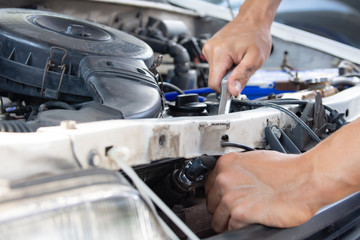 The mechanic used a wrench to remove the spark plug from a car. Mechanic inspect and repair the damaged car. 