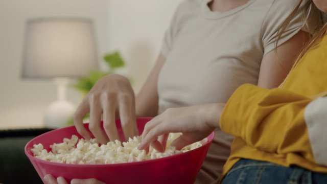 Sister Girls Watching a Movie and Eating Popcorn in Couch