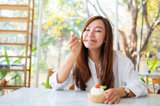Closeup image of a beautiful asian woman enjoy eating an ice cream in restaurant