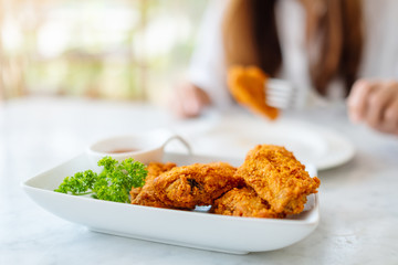 Closeup image of a woman eating fried chicken in restaurant