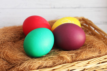 four Easter colored eggs lying on the hay in baskets