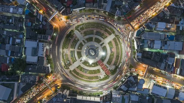 Hyperlapse timelapse of night city traffic on 4-way stop street intersection circle roundabout in bangkok, thailand. 4K UHD horizontal aerial view.