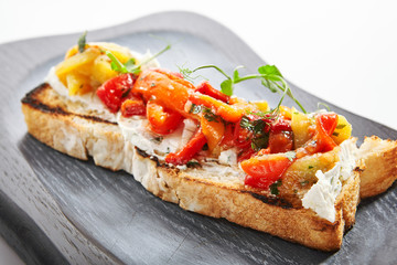 Fototapeta na wymiar Delicious bruschetta with baked peppers close up view