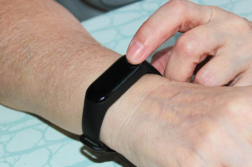 Fitness bracelet on a woman's hand. Pedometer, a woman measures the pressure.