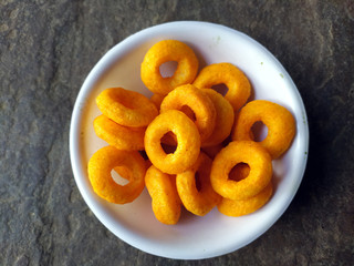 SOME YELLOW EATABLE FOOD PUT IN A BOWL ON STONE BACKGROUND