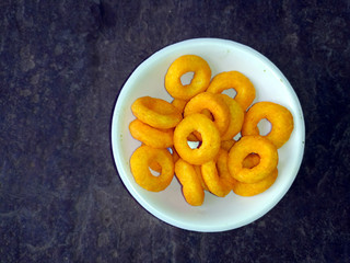 SOME YELLOW EATABLE FOOD PUT IN A BOWL ON STONE BACKGROUND