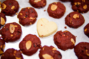 Love shape cookies in the middle of red velvet cookies on a tray