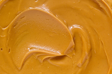 Peanut butter texture background. Brown nut paste smear closeup. Delicious natural food creamy smooth spread macro top view - obrazy, fototapety, plakaty