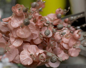 Pink scones of artificial flowers with buds on a branch, background backdrop decoration design close-up. Bouquet of fake flowers for interior decoration