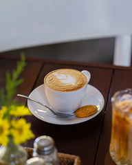 A cup of latte is photographed with selected focus on the table.