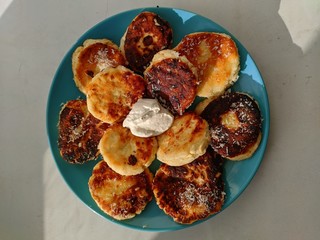cheesecakes with sour cream in a blue plate, on a white background