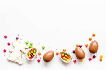 Fototapeta na wymiar Sweet Easter symbols - chocolate eggs and bunny gingerbread - on white background top-down frame copy space