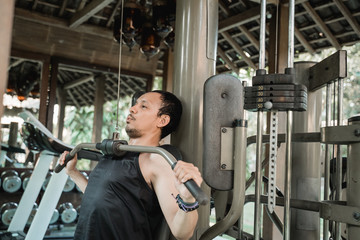 Asian man workout with lat pulldown machine in the gym house