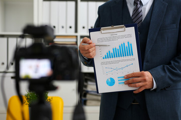 Male in suit and tie show stats graph pad making promo videoblog or photo session in office...