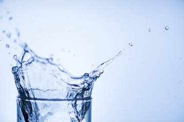 Cropped close up image of glass top full of tasty fresh clear drinkable tap water with high splash isolated over light blue white background with blank place for text