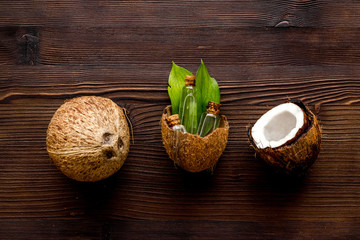 Coconut cosmetics. Organic oil in small bottles on dark wooden background top-down