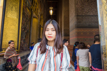 Asian cute women travel in golden reclining buddha statue indoor temple pagoda