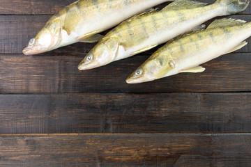 Fresh frozen freshwater fish on a dark wooden table. Top view, copy space, minimalist concept