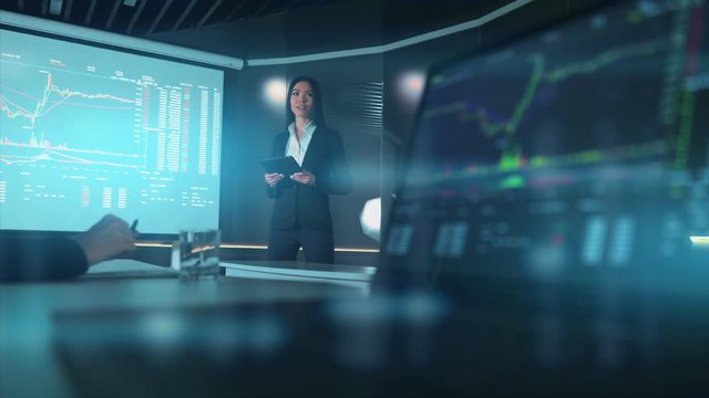 The businesswoman standing near the large screen with presentation