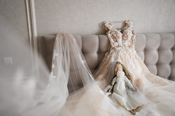  wedding white dress lying on the bed on a white background with a decorative doll