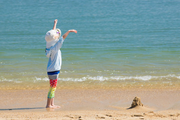 Fototapeta na wymiar 海の砂浜で遊んでいる可愛い子供