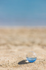 夏の海の砂浜にある透明な水晶ガラスボール