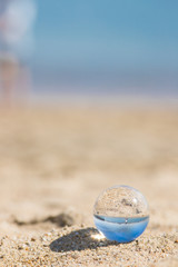 Fototapeta na wymiar 初夏の海の砂浜で遊んでいる子供姉妹と透明な水晶ガラスボール