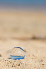 Fototapeta na wymiar 夏の海の砂浜にある透明な水晶ガラスボール