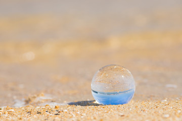 Fototapeta na wymiar 夏の海の砂浜にある透明な水晶ガラスボール