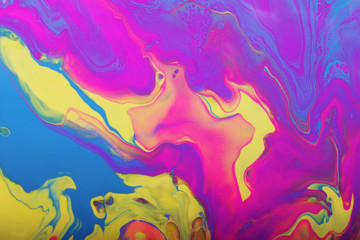 Obraz na płótnie Canvas Colorful marble background.Mixed nail polishes-yellow,pink,blue and purple.Beautiful stains of liquid nail polish,fluid art technique.Pour painting technique.
