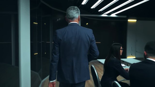 The old businessman walking into the room and talks to colleagues. slow motion