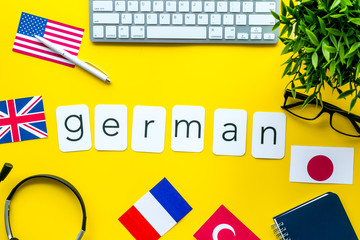 Learn German online. Concept with text, headset and keyboard on yellow background top-down