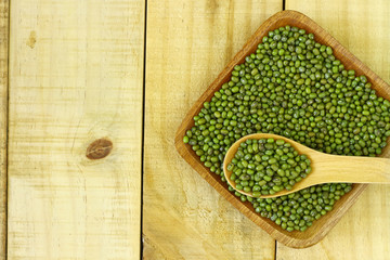mung beans in wooden bowl and spoon on wooden table top. Copy space for text or editorial.